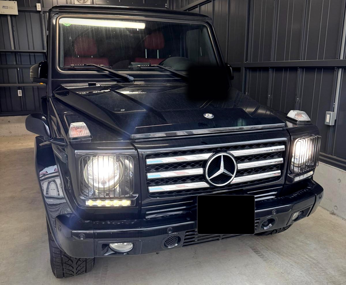 Czarny Mercedes-Benz klasy G z włączonymi światłami, widok z przodu